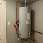 Modern utility room with new water heater installation, clean pipes, and polished chrome plumbing fixtures